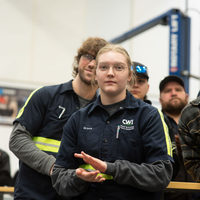 A CWI student, surrounded by others, applaud during an event.