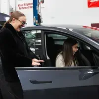 CWI students smile as they inspect a newly delivered Tesla, recently acquired by the College.