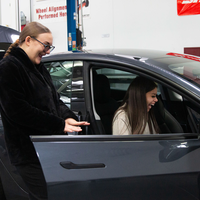 CWI students smile as they inspect a newly delivered Tesla, recently acquired by the College.