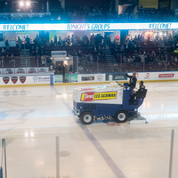 A zamboni on the ice at a hockey game.