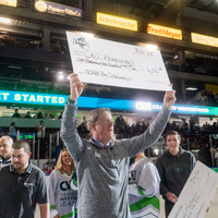 A man holds a ceremonial check on the ice of a hockey game. 