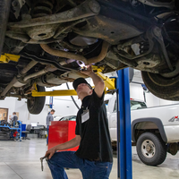 A student performs maintenance on a car.