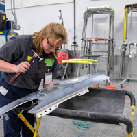 A student holding a hammer works on a piece of metal.