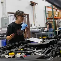A student checks the oil guage on a car.
