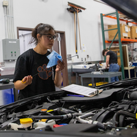 A student checks the oil guage on a car.