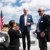 A woman talks to two men in suits as they prepare for a public address.
