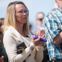 A woman in an audience smiling and applauding.