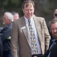The President of CWI laughs with 2 men as they stand outdoors at a ceremony celebrating a bridge signing.
