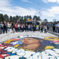 A large group of people launch confetti from confetti cannons to celebrate the completion of a new bridge on CWI campus.