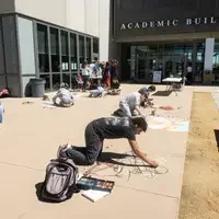 Students draw murals on the sidewalk in front of the CWI Academic building.
