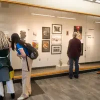 Students and faculty browse artwork displayed on a gallery wall during the CWI 2024 Connections Project.