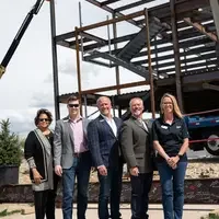 Idaho state legislatures and College of Western Idaho Trustees pose in front of a construction site.