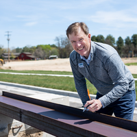 CWI president Gordon Jones signs his name on a metal beam destined for a new Health and Sciences building.