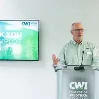 Donors and College representatives attend a sign unveiling at a new building on campus.
