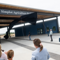 Donors and College representatives attend a sign unveiling at a new building on campus.