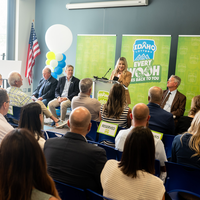A speaker stands at a podium addressing an audience.