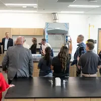 A group of people are led on a guided tour of a new college campus building.