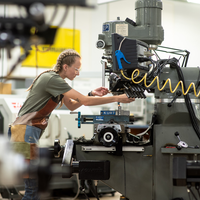 A student machinist works at a machine.