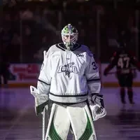 A hockey goalie in full gear stands on the ice.