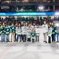 People pose for a photo on the ice during a hockey game.