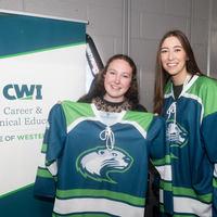 Two women pose for a photo wearing hockey jerseys.