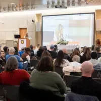 Students listen to speakers at a graduation and then receive their pins, signifying graduation.