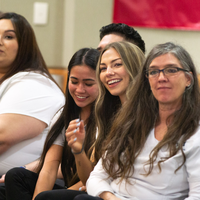 Students listen to speakers at a graduation and then receive their pins, signifying graduation.