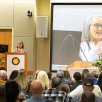 Students listen to speakers at a graduation and then receive their pins, signifying graduation.