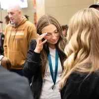 Students listen to speakers at a graduation and then receive their pins, signifying graduation.