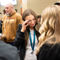 Students listen to speakers at a graduation and then receive their pins, signifying graduation.