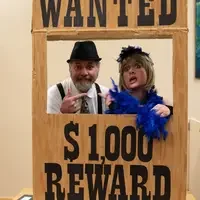 Couple by a Wanted sign posing for a picture