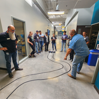 Group of people in a hallway looking at a track on the floor