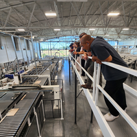 Group of people standing near a railing and looking down on a factory floor