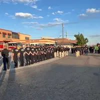 Group of firefighters and cadets standing in formation outside Nampa Fire Station during a ceremony, with fire trucks parked in 