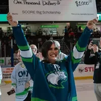 Mackenzie Nash holds a check above their head