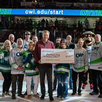 Group of people holding scholarship check on the ice