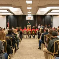 Speaker on stage in a room full of people.
