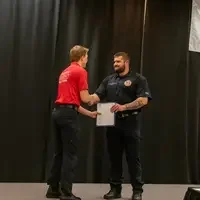Graduate receiving an award and shaking hands on stage.