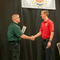 Graduate receiving a certificate and shaking hands on stage.