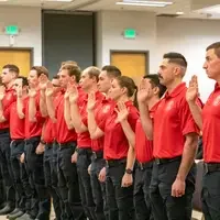 A row of graduates with their right hands raised.