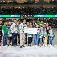 The winner of a $1000 scholarship is awarded a big check on the ice of a hockey rink.
