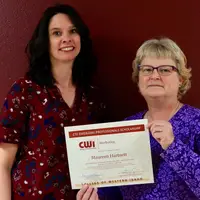 Student standing holding a Emerging Professionals certificate and standing next to instructor
