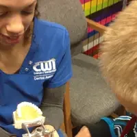 Dental Assisting Program student demonstrating oral health with little boy.
