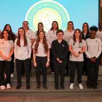 Group of people standing on a stage in front of projector screen