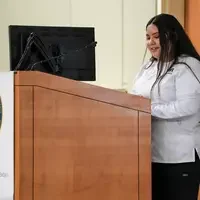 Student reads notes behind podium near a TV 