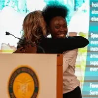 Two people hugging behind podium