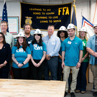 A group of students and executives pose for a photo.