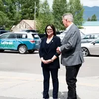 Two people visit in a parking lot.