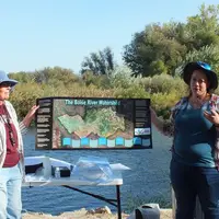 Two women giving presentation with large poster.
