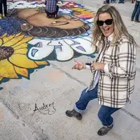 A woman smiles and points to her signature on the surface of a newly constructed bridge.